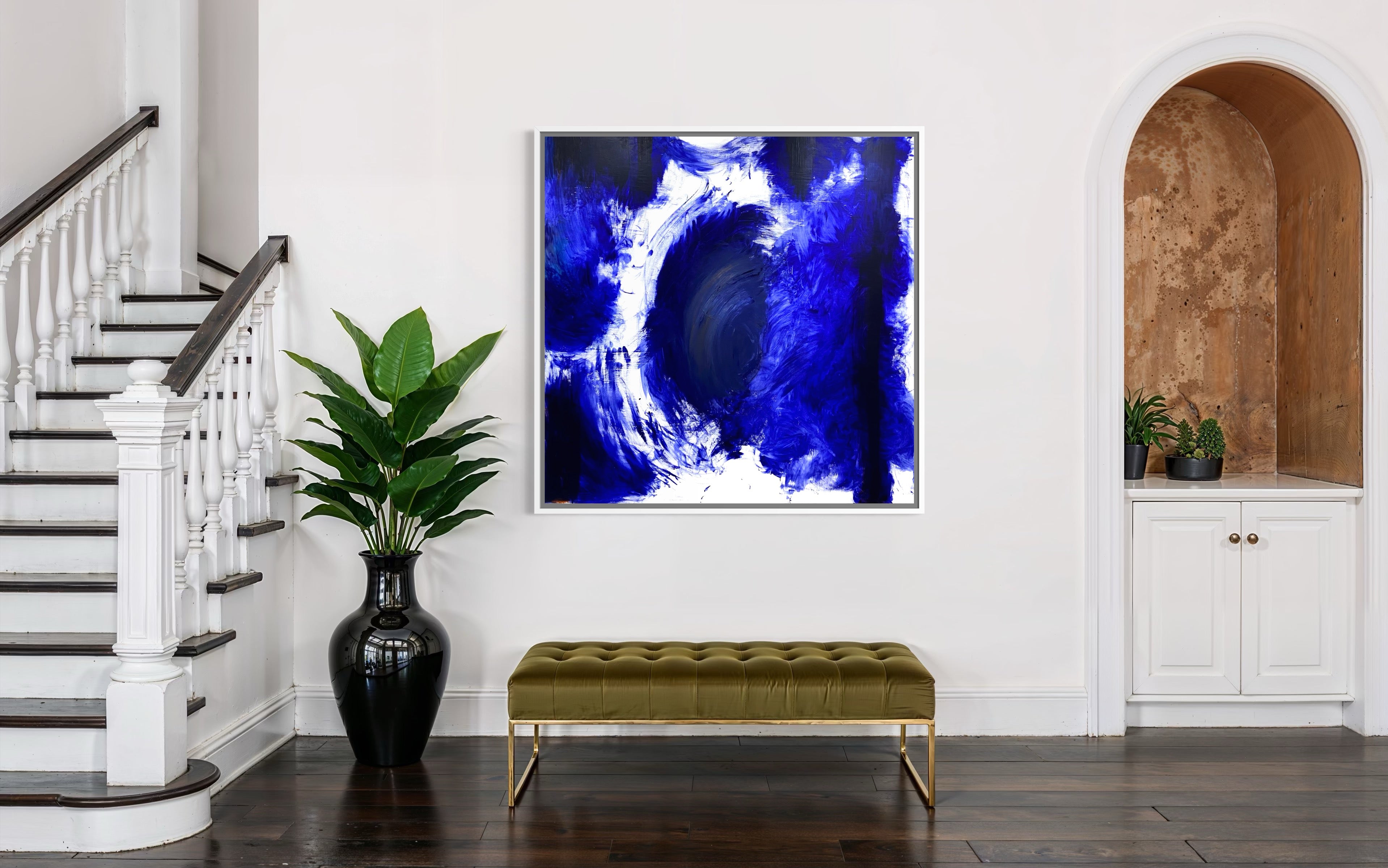 Modern interior with abstract blue artwork on a white wall, green bench, and plant.